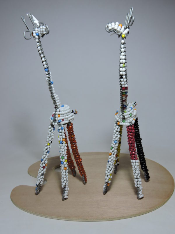 Bead and wire sculpture of a white giraffe with red and black legs and blue beads on its neck.