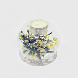 Glass sphere tealight holder with reflective surface, with tealight candle and some yellow flowers in the glass sphere.